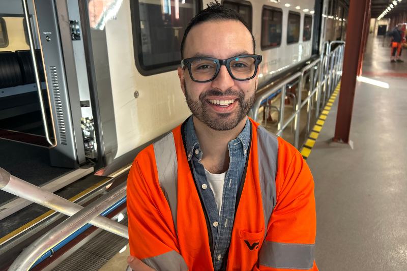 Gritzko fordonschef. Man med glasögon och orange väst står inomhus framför tåget ER1