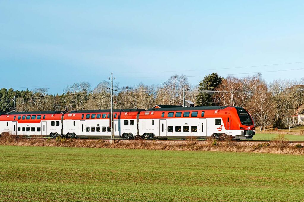 Tåg i Bergslagens nyaste fordon ER1 på spårer intill ett vårgrönt fält.